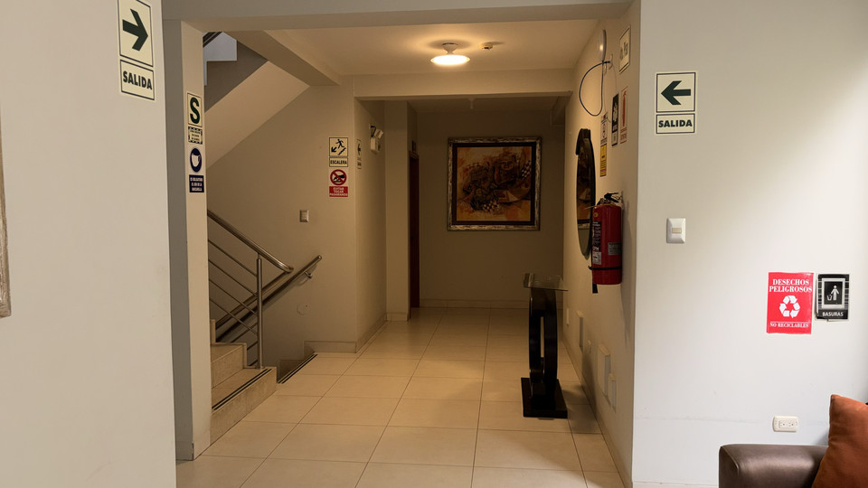 Pasillo hacia las habitaciones, con señalización de seguridad y extintor