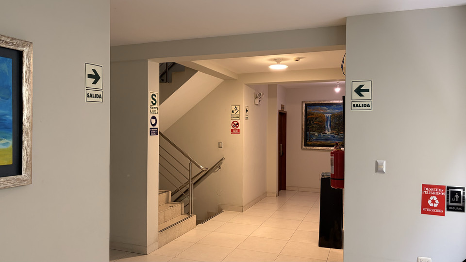 Zona de espera en el pasillo del hotel, con sillón y señalización de salida