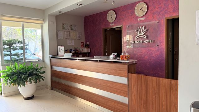 Counter de recepción del Cacique Hotel, con el logotipo sobre la pared morada
